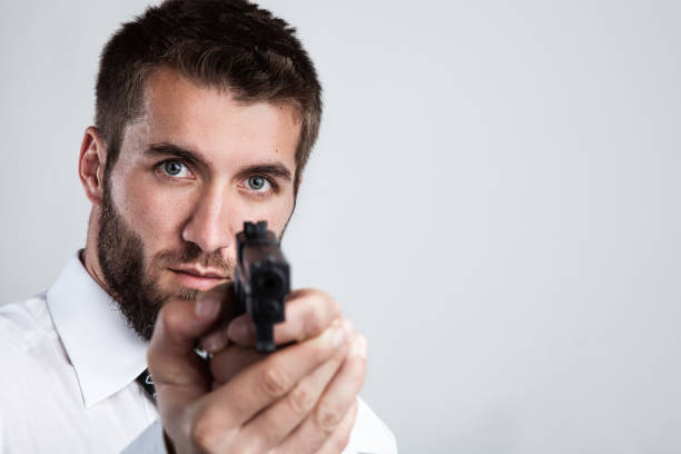 Attractive man with a beard is pointing at you with a gun