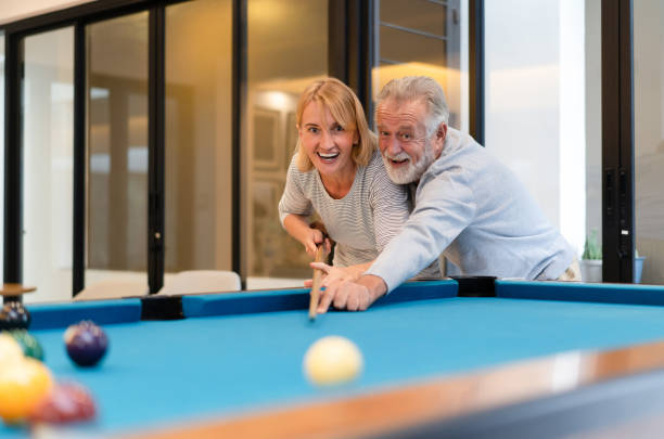 amoureux dans un salon. couple aîné heureux jouant le billard ensemble dans la maison. - snooker photos et images de collection