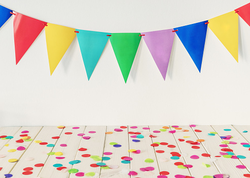 Empty wooden table top with colourful confetti and bunting