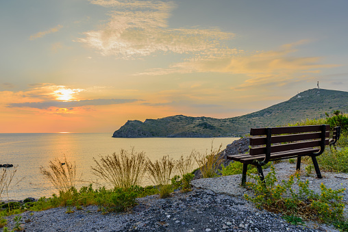 Beautiful sunset on the sea. Viewpoint with a bench on top of a hill. Skala village on Patmos island, Dodecanese, Greece.