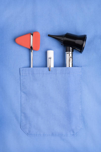 Doctor's Pocket The pocket of a doctor's scrubs containing an otoscope, flashlight and reflex hammer. rubber mallet stock pictures, royalty-free photos & images