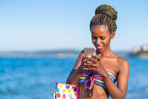 istock African woman having fun at the beach and using smart phone 1135811052