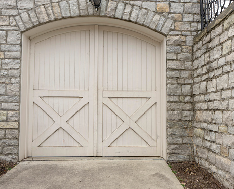 Arched wooden garage door with stone wall surrounding.  Horizontal view.  Could be used as background.