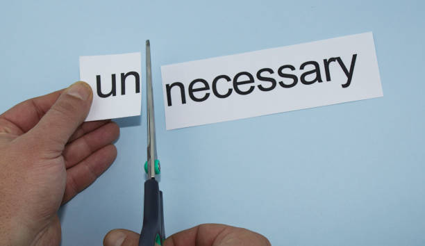 istock necessary and unnecessary. Hand cutting paper with scissors 1135815329