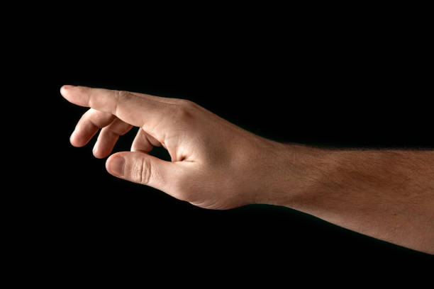 istock Man's hand touching or pointing to something isolated on black background. Close up. High resolution. 1135816789