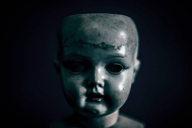 Close up Vintage doll face, red smile thin hand painted eyebrows and  blue eyes on a old cracked face on flea market.