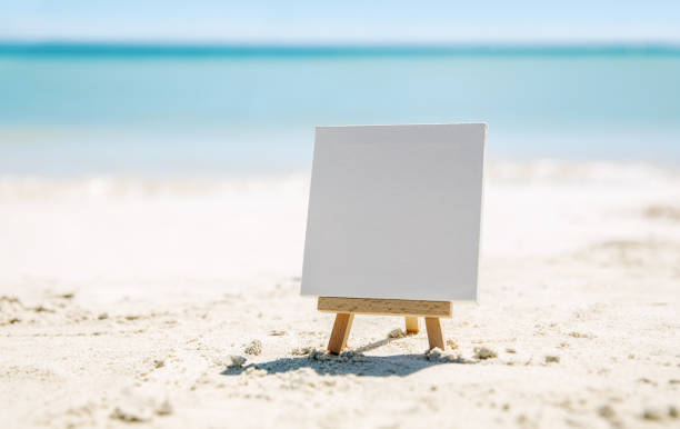 um cavalete com uma lona branca pura na praia do oceano. - easel blackboard isolated wood - fotografias e filmes do acervo