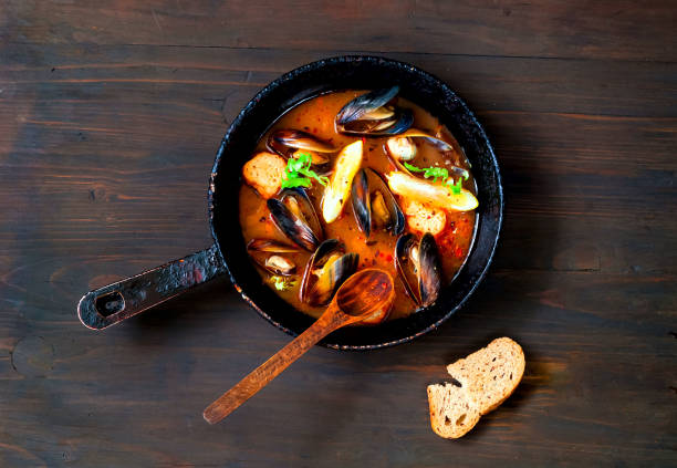 Mussels in red curry sauce on a wooden background.The concept of  healthy and satisfying appetizer or light meal.Close-up, copy space.