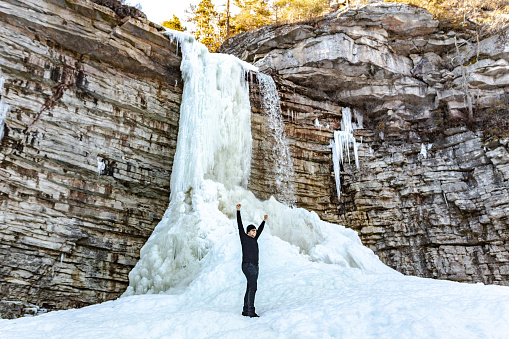 Men in front of a frozen waterfall during winter in a mountain in New York State.