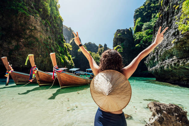 junge frau an einem schönen strand in thailand mit longtail-booten, phi phi island - phi stock-fotos und bilder