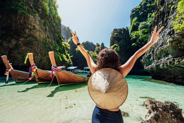 Young woman on a beautiful beach in Thailand with longtail boats, Phi Phi Island