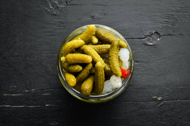 istock Marinated cucumbers in a jar on a black wooden kitchen table. Top view. Free space for your text. 1135835550