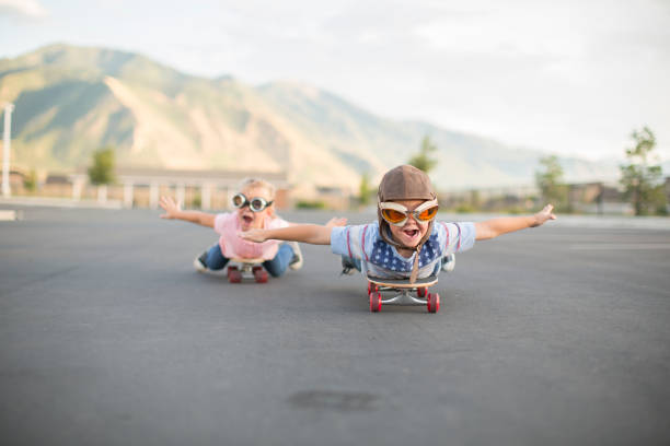 young boy und girl flying auf skateboards - taking off business creativity adventure stock-fotos und bilder