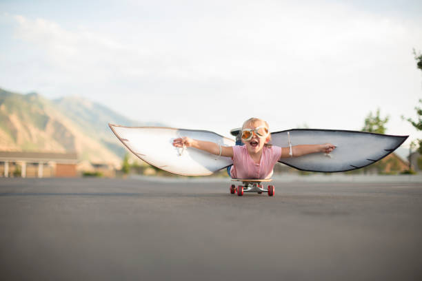 翼を持つスケートボードに飛ぶ若い女の子 - action adventure aerospace industry air vehicle ストックフォトと画像