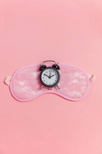 istock Sleeping mask and alarm clock on pink background 1135839242