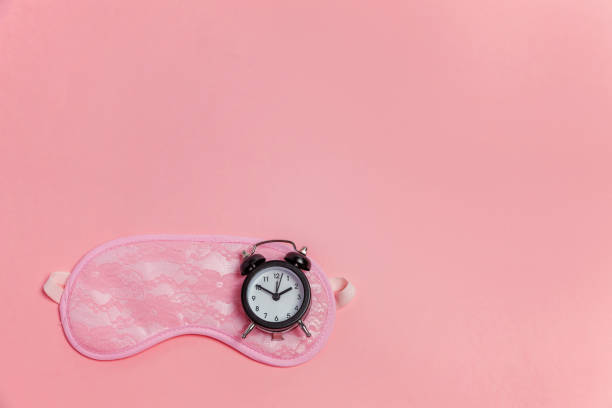 istock Sleeping mask and alarm clock on pink background 1135839252