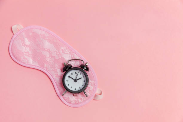 istock Sleeping mask and alarm clock on pink background 1135839278