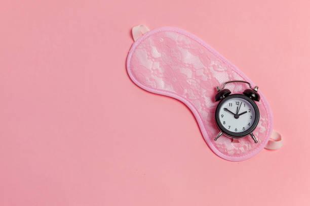 istock Sleeping mask and alarm clock on pink background 1135839303
