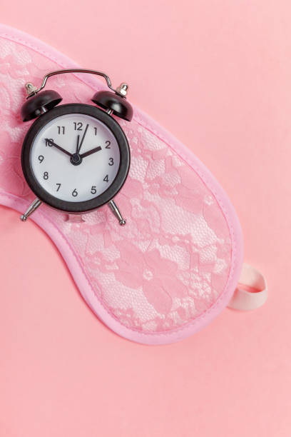 istock Sleeping mask and alarm clock on pink background 1135839340