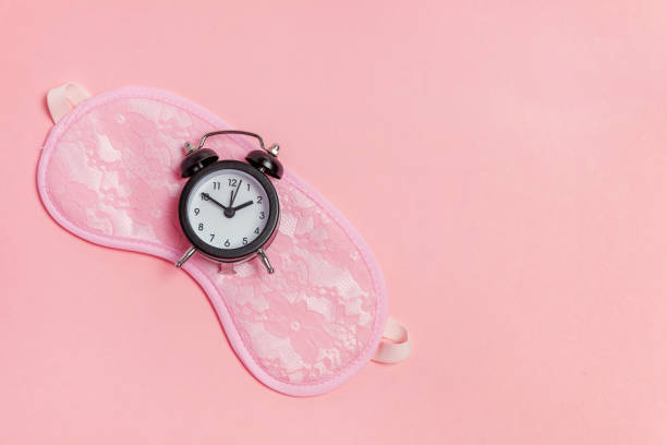 istock Sleeping mask and alarm clock on pink background 1135839345