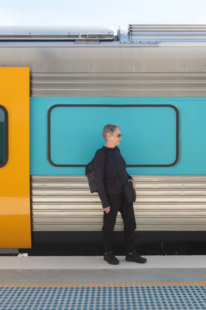 istock Senior woman with backpack standing next to colourful train 1135839371