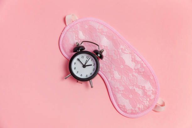 istock Sleeping mask and alarm clock on pink background 1135839385