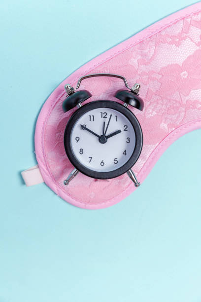 istock Sleeping mask and alarm clock on blue background 1135840218