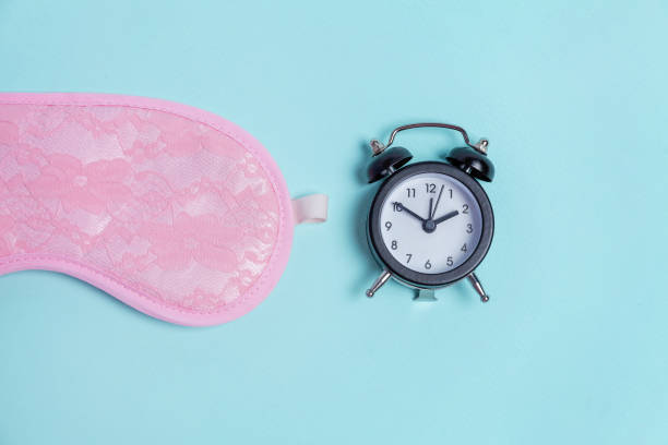 istock Sleeping mask and alarm clock on blue background 1135840240