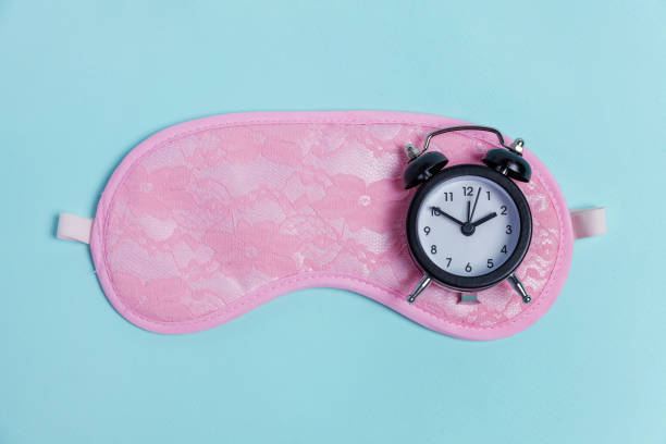 istock Sleeping mask and alarm clock on blue background 1135840254