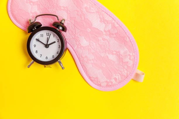 istock Sleeping mask and alarm clock on yellow background 1135840294