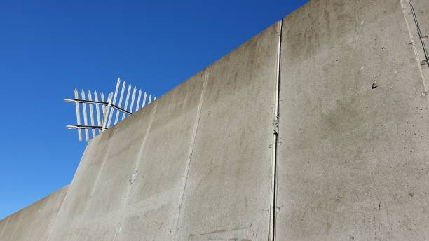 istock Concrete wall with spiked metal fence against blue sky with copy space 1135841627