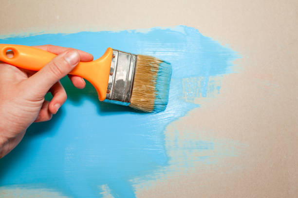 istock paint brush in hand paints with blue paint 1135847729