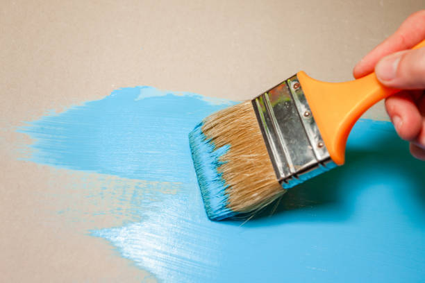 istock paint brush in hand paints with blue paint 1135847730
