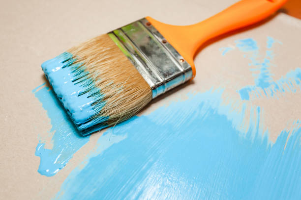 istock paint brush in blue paint on an unpainted flat surface 1135847737