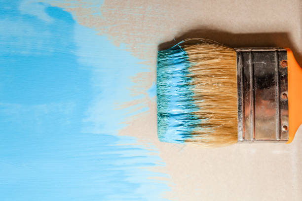 istock paint brush in blue paint on an unpainted flat surface, copyspace 1135847744