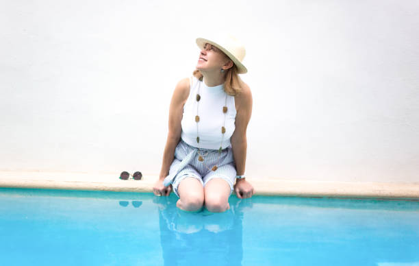 active senior: donna felice al bordo della piscina - women wading sun hat summer foto e immagini stock