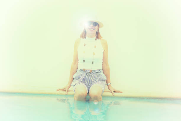 senior attivo: donna felice al bordo della piscina - women wading sun hat summer foto e immagini stock