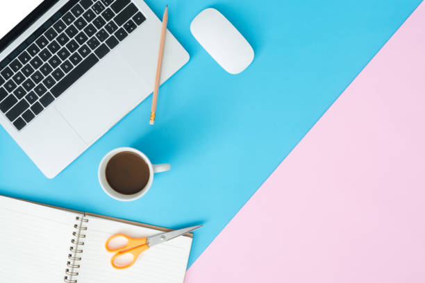 istock Creative flat lay photo of workspace desk. Top view office desk with laptop, pencil, notebook, coffee cup and mouse on blue pink color background. Top view with copy space, flat lay photography. 1135855331