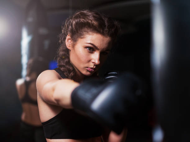 istock Young fighter boxer girl in training with heavy punching bag 1135863368