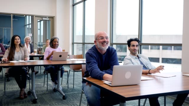 Happy group of mixed age, multi-ethnic college students attending class