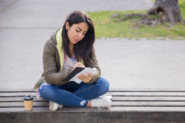 istock Busy student girl writing down ideas in diary 1135880677