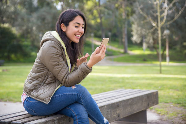 istock Excited young woman chatting online in park 1135880680