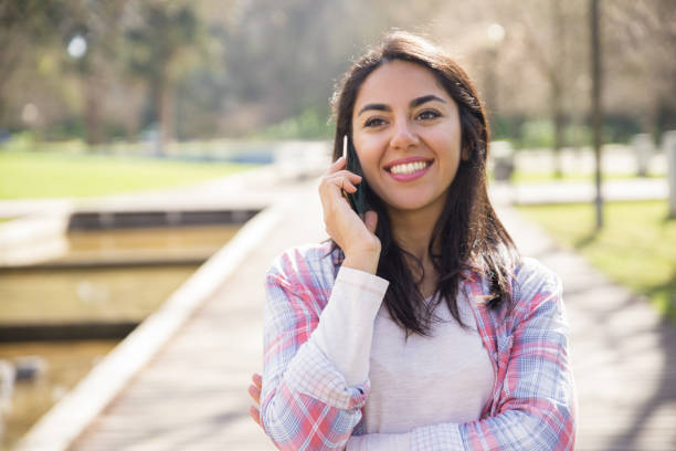 istock Cheerful student girl talking on cell in city park 1135881015