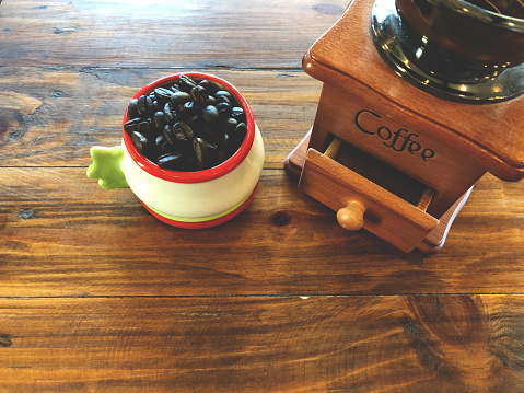 Vintage Manual Coffee grinder and Dark roast coffee beans in cup on the vintage wooden table. Love coffee concept. Vintage dark light style. Copy space