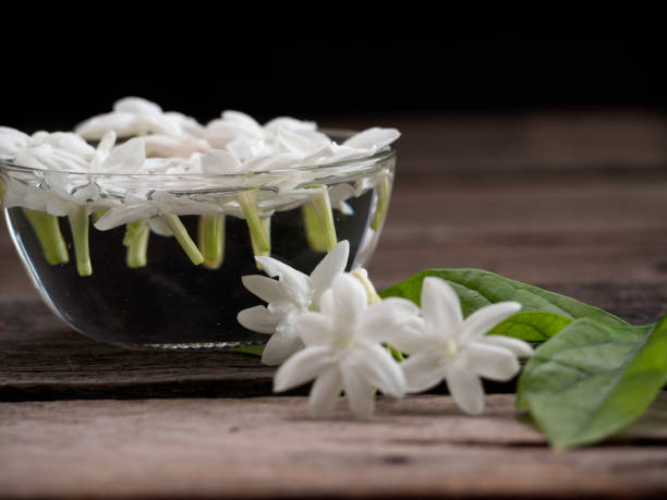 istock Jasmine floating in clear glass  on wooden background 1135898636