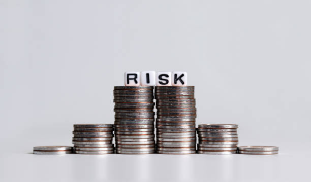 istock 'RISK' text white cube on the pile of coins. 1135898706
