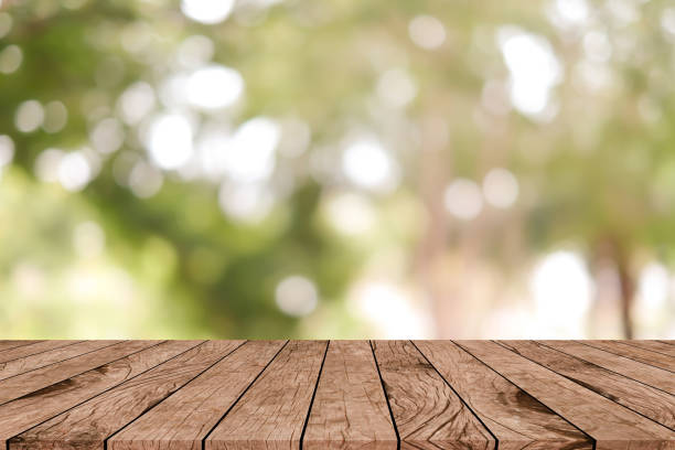 istock abstract blurred greenery leaves of tree in home garden backyard with sunlight glow and vintage brown color wood plank table for show product on display concept 1135900636