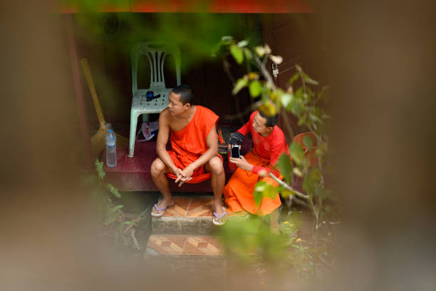 Luang Prabang, Laos, February 11, 2019. (selective focus) Two Buddhist Monks, framed by a wall with arches are talking each others in Luang Prabang, Laos. The Buddhist monk is who, at the age of twenty, confirms the ordination after a period of novitiate.
