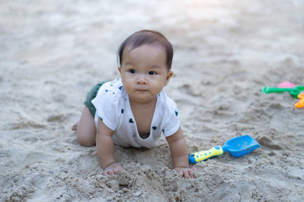 istock Cute Baby Boy Looking Away While Kneeling On Sand At Playground 1135916546