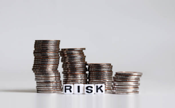 istock 'RISK' text white cube and pile of coins. 1135917519